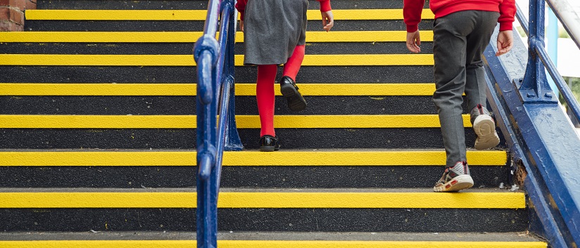 shot of two schoolchildren's legs walking up steps at a school they are wearing red sweatshirts