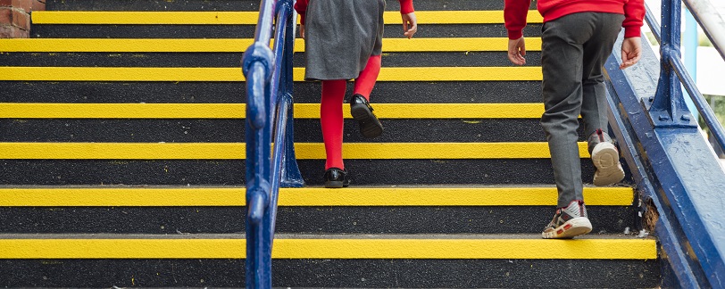 shot of two schoolchildren's legs walking up steps at a school they are wearing red sweatshirts