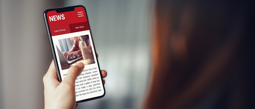 hand holding a phone with a news article on it