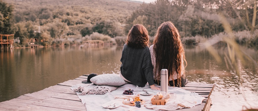 two women sat at a lake in autumn 